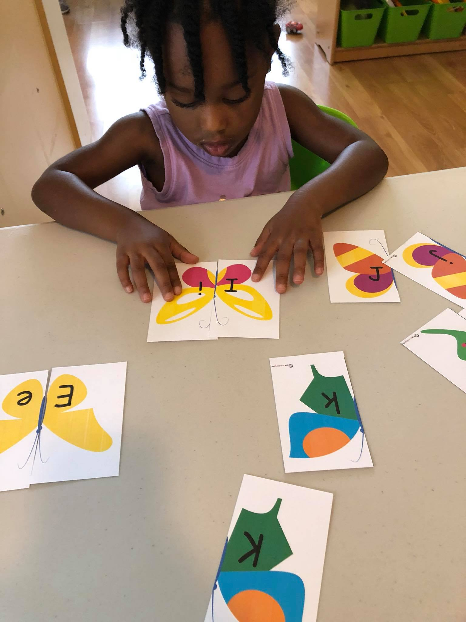 Child matching butterfly letter cards at a table